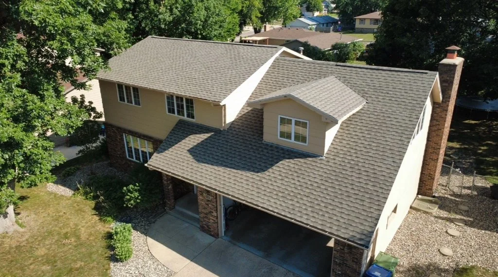 Two-story home with new gray architectural asphalt shingle roof installation, multiple roof planes and gable sections