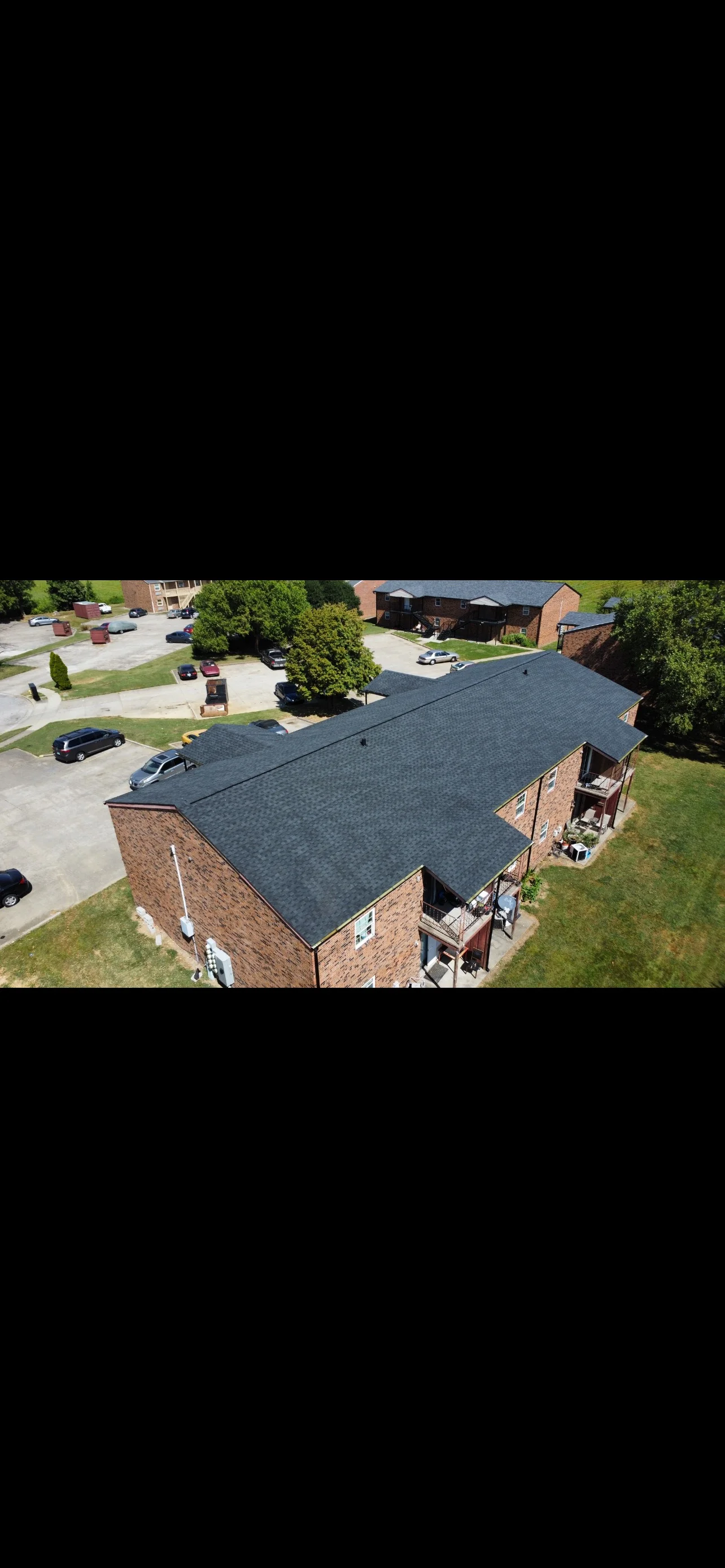 Aerial view of brick home with new charcoal gray asphalt shingle roof installation
