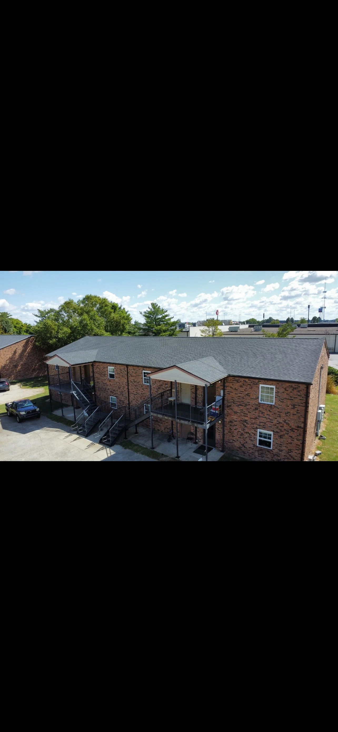 Multi-unit brick building with new charcoal gray asphalt shingle roof installation
