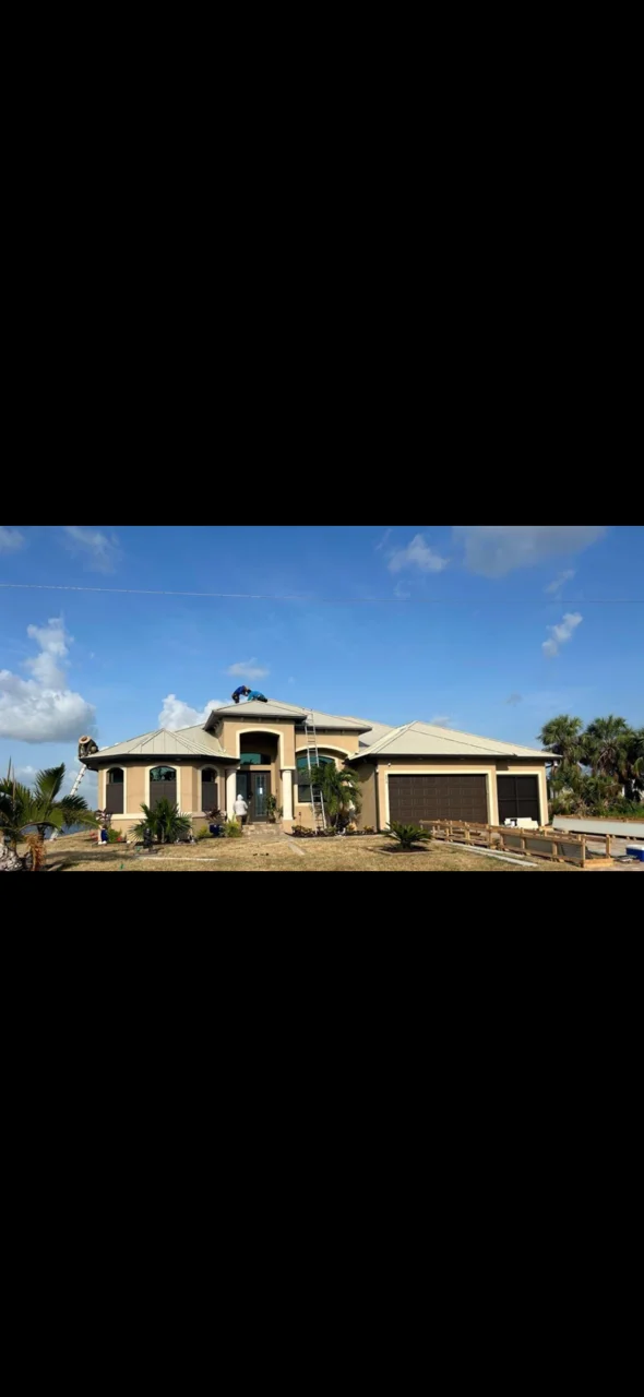 Two-story home with newly installed standing seam metal roof in tan finish