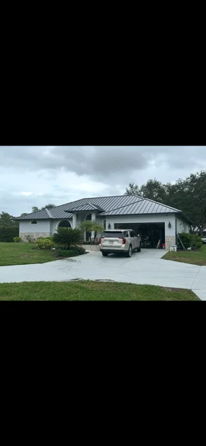 Standing seam metal roof installation on modern residential home with dark gray finish