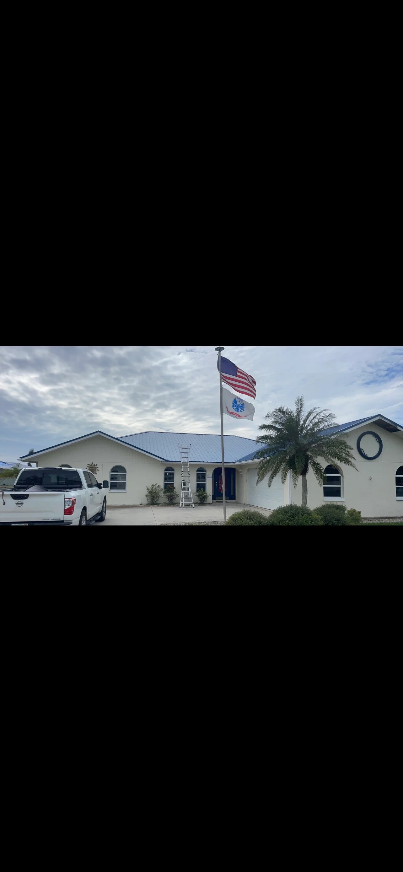 Standing seam metal roof installation on white commercial building with blue-gray finish