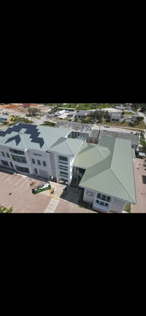 Aerial view of standing seam metal roof installation on commercial building with gray-green panels