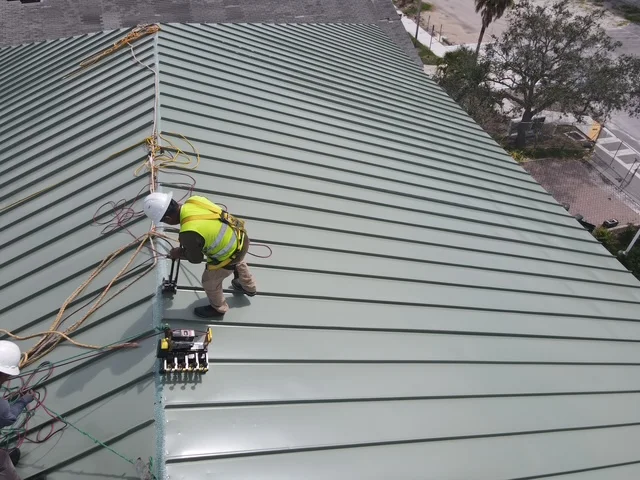 Worker installing standing seam metal roofing panels on residential roof structure