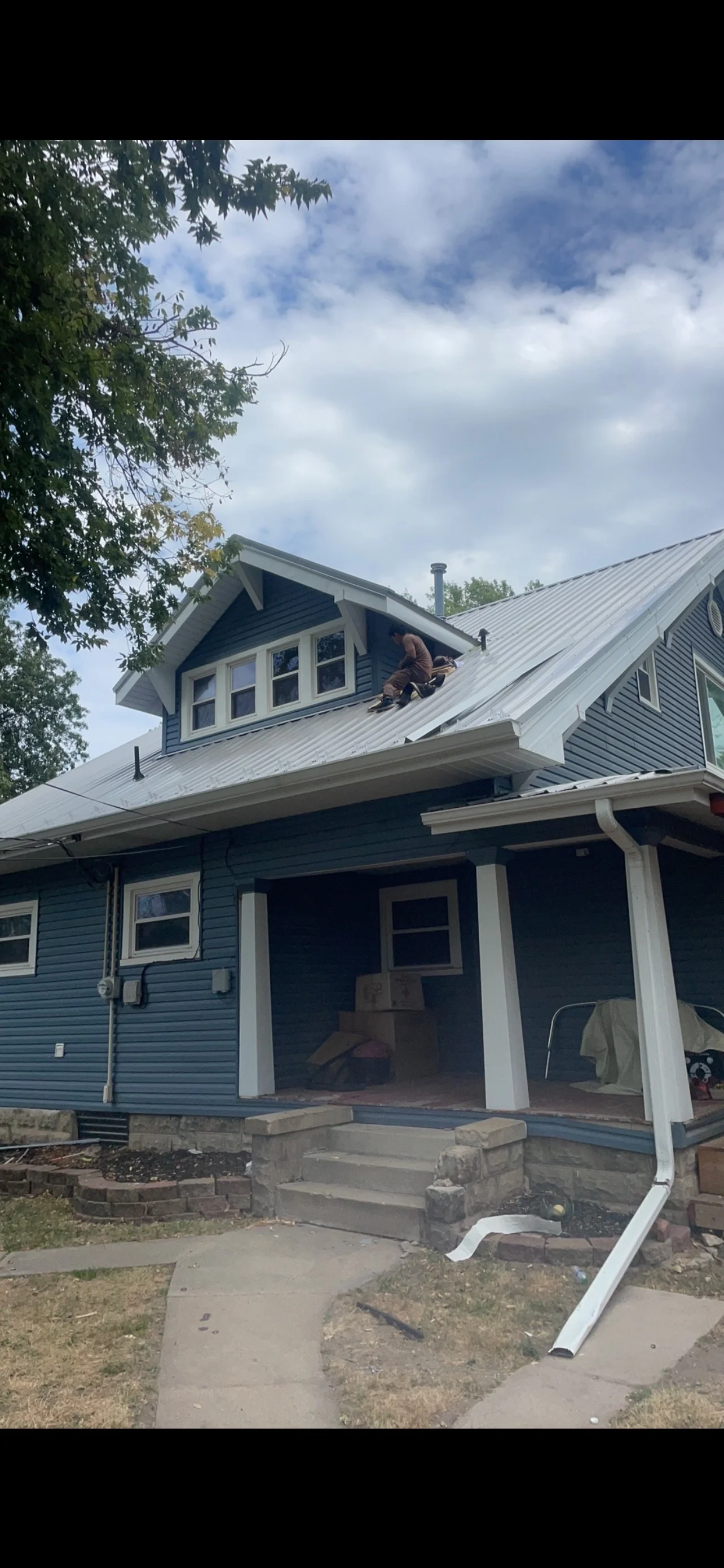 Metal standing seam roof installation on residential home with gable vent and white trim