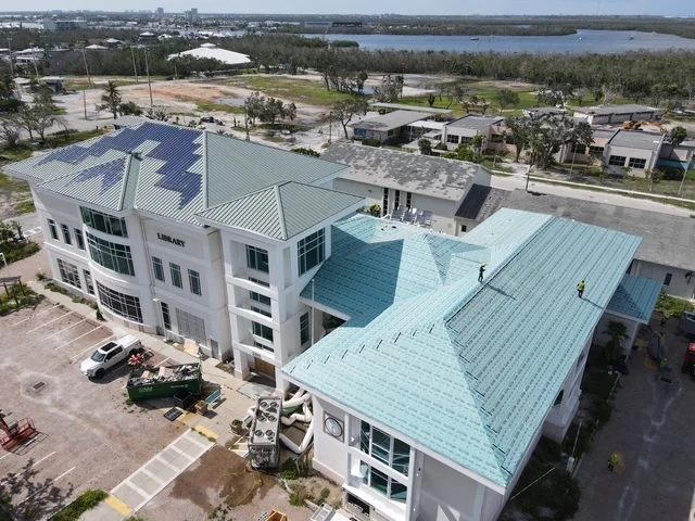 Aerial view of modern home with standing seam metal roof in blue and gray panels
