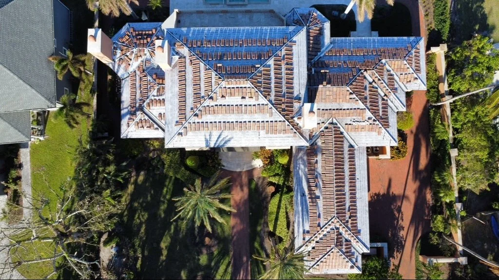 Aerial view of clay barrel tile roof installation on multi-section home with complex roof geometry