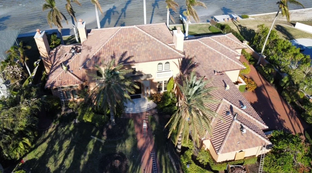 Aerial view of clay barrel tile roof replacement on waterfront home with multiple sections and dormers