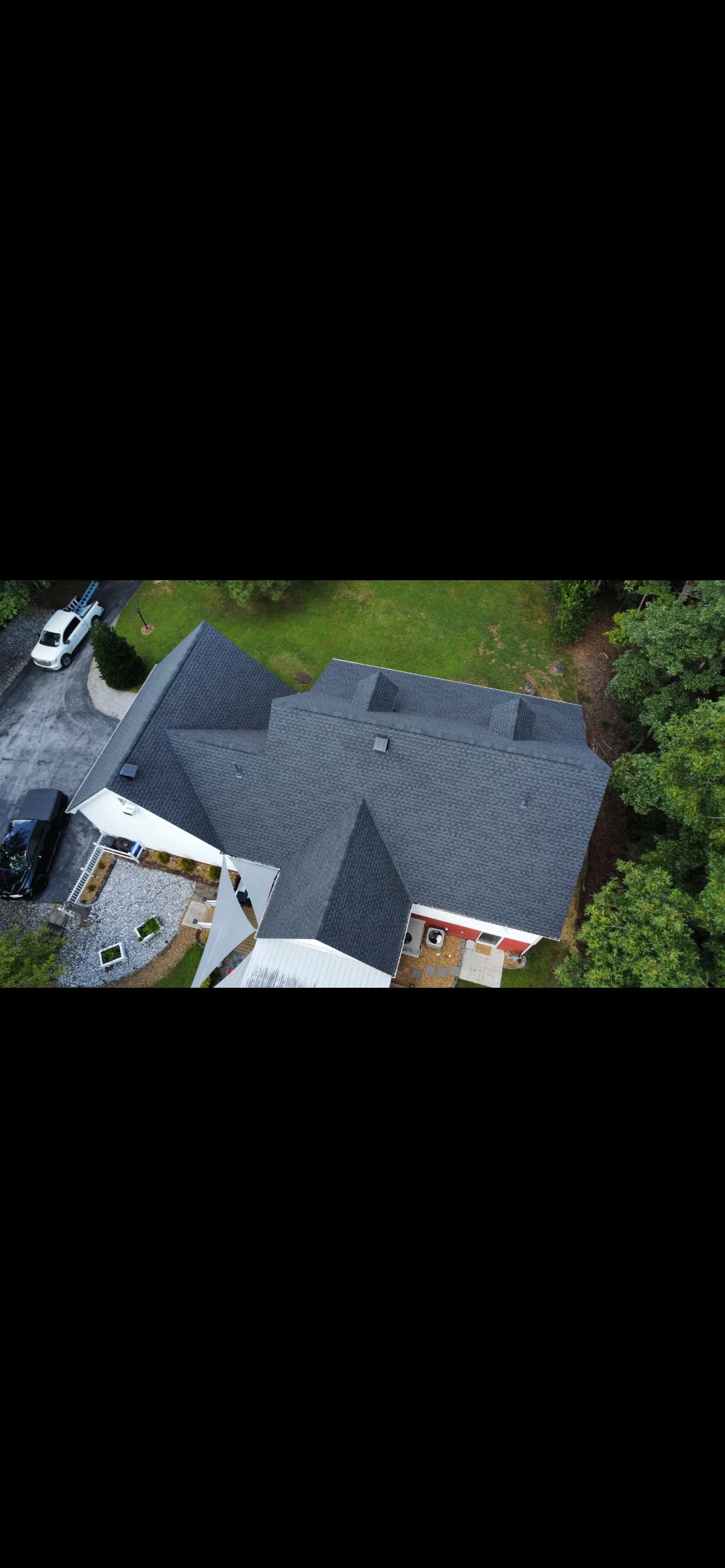 Aerial view of completed asphalt shingle roof with multiple gables and valleys on residential home