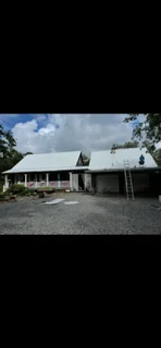 Metal standing seam roof installation on residential home with white trim and stone foundation