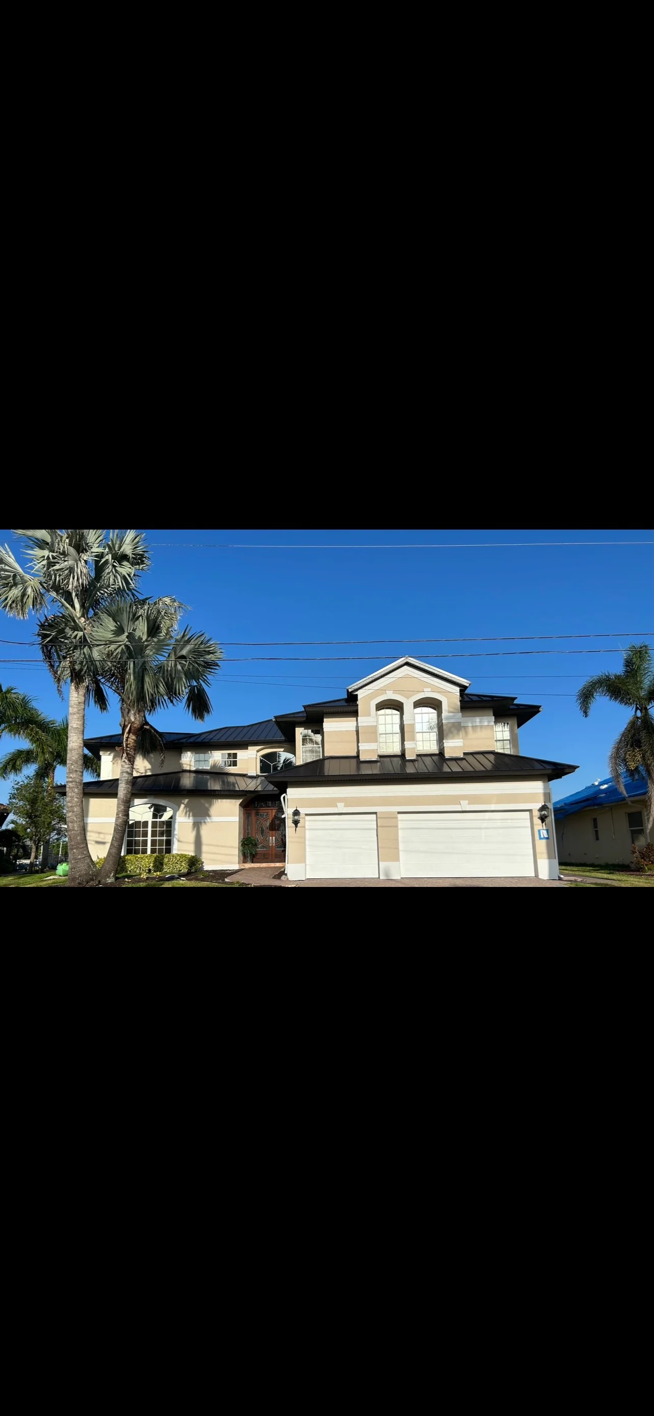 Two-story home with new architectural shingle roof and black metal roof accents